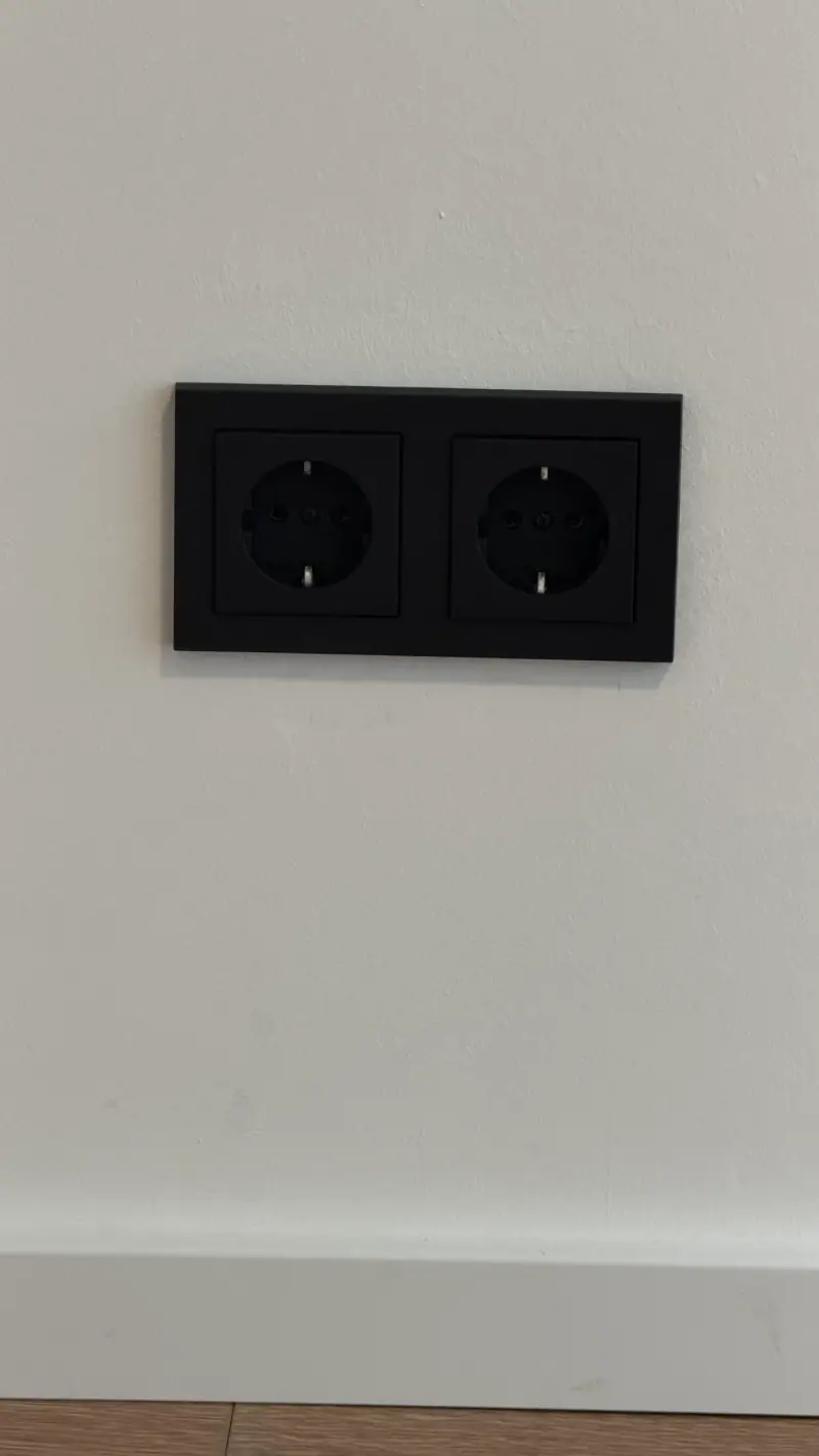 Neue schwarze Doppelsteckdose an einer weißen Wand