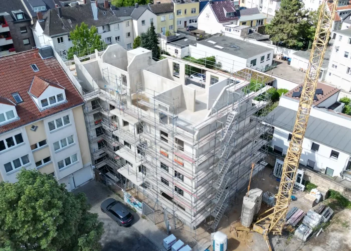 Luftaufnahme einer Baustelle in urbanem Wohngebiet, mehrstöckiges Gebäude mit Gerüst und Kran