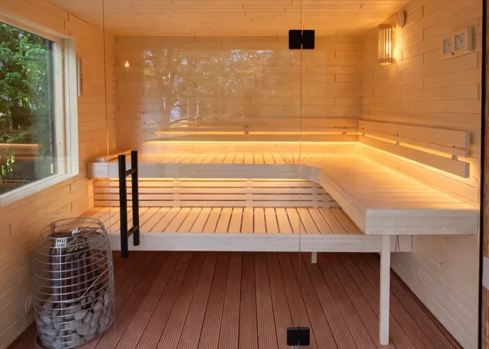 Innenraum einer Holzsauna mit Sitzbänken, Glastür und installierter Infrarotheizung an der Decke